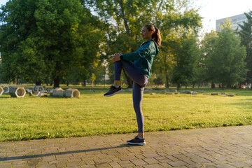 Full lenght portrait of beautiful fitness woman stretching before morning outdoor workout in the city park. © Halfpoint
