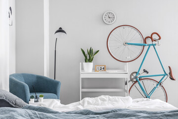Interior of light children's bedroom with cozy bed, armchair and bicycle