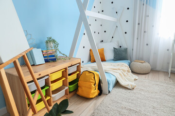 Interior of children's bedroom with cozy bed, shelving unit and easel