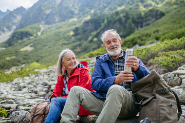 Active senior couple hiking together in autumn mountains.