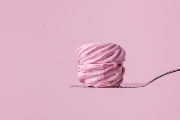Macro shot of single pink berry homemade marshmallow on confectionery spatula. Zefir dessert with red currant mousse on the pink pastel background.