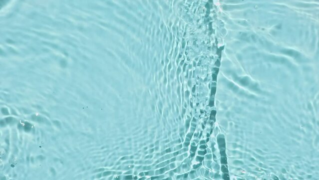 Pure water with reflections sunlight in slow motion. Water surface texture top view. Sun and shadows. Motion clean swimming pool ripples and wave. High quality 4k footage. 