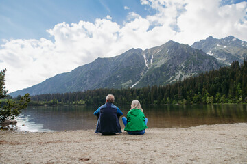 Rear view of senior couple resting after hiking in autumn mountains.
