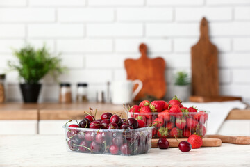 Plastic containers with fresh berries on table in kitchen