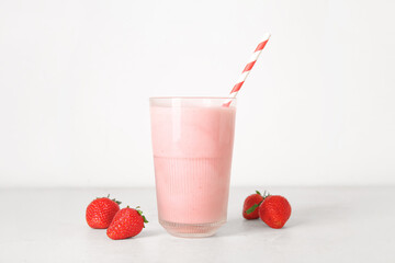 Glass of tasty strawberry smoothie on light background