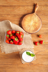 Glass of tasty strawberry smoothie on wooden background