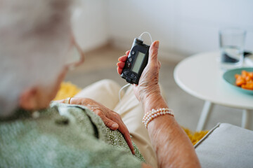 Close up of diabetic senior patient checking her blood sugar level on insulin pump.