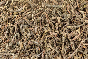 Food background.Textural contrasting background of dry black tea leaves.Macrophoto