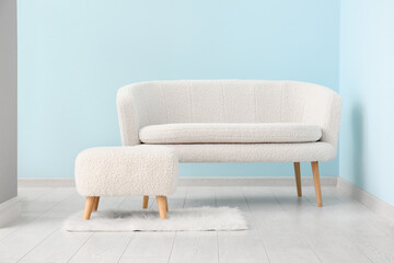 White sofa and pouf near blue wall