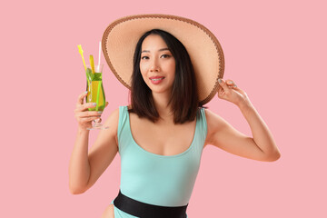 Beautiful Asian woman in swimsuit and with Mojito cocktail on pink background
