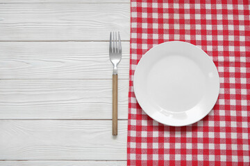 Clean plate, fork and napkin on white wooden background