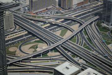An aerial view of a stack interchange in Dubai. Freeways, onramps and offramps flow past, over, and under one another in an example of grade separation in road planning.