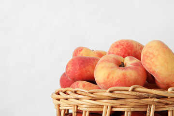 Wicker bowl with sweet fig peaches on white background