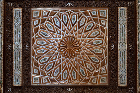 On the door of a mosque's entrance, a design of carved wood, bone, and mother of pearl. The geometric design is a strong example of Islamic art and design.