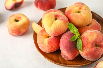 Wooden plate with sweet fig peaches and mint on white background