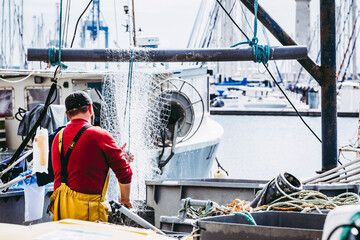 Pêcheur en train de nettoyer et ranger les filets de pêche sur le port © PicsArt