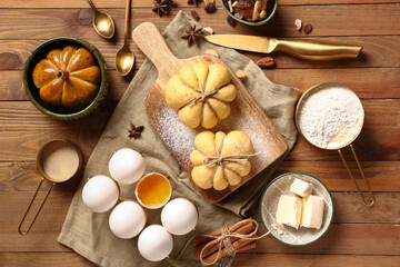 Board with pumpkin shaped buns and ingredients on wooden background