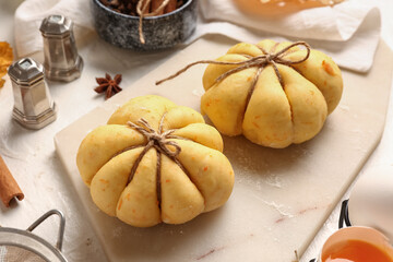 Board with pumpkin shaped buns on white background