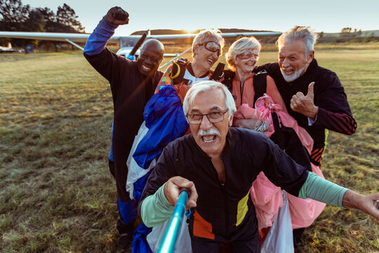 Group of senior people taking a selfie after skydiving on a field