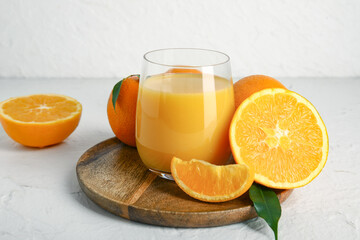 Wooden board with glass of fresh orange juice on white background