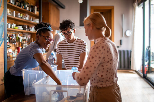 Young and diverse group of friends roommates recycling plastics and bottles in their flatshare apartment