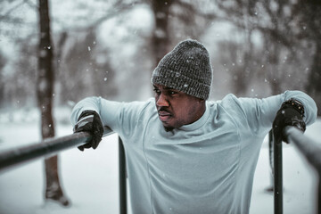 Young athletic and fit african man exercising and working out in a outdoors park during winter and snow