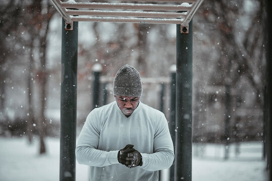 Young athletic and fit african man exercising and working out in a outdoors park during winter and snow