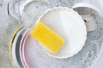 Dishes and bowls in water and bubbles of dishwashing liquid. Kitchen work