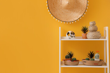 White shelving unit with decorative human skull and sombrero hanging on yellow wall