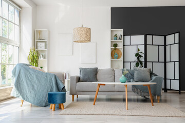 Interior of light living room with armchair, grey sofa and coffee table