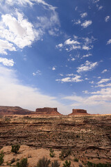 mesas under a blue sky with clouds at noon