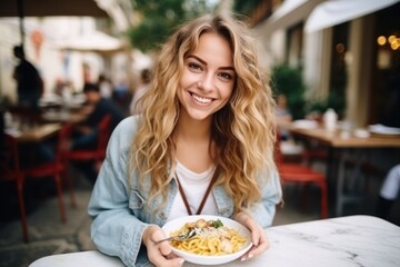 Girl eats pasta in street cafe