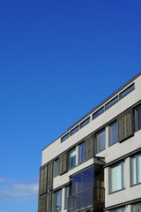 Fototapeta na wymiar View to white appartment building with wooden details towards blue sky. Tallinn, Estonia