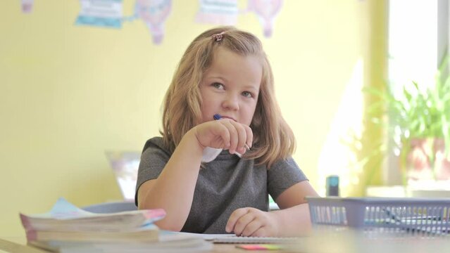 girl schoolgirl sitting at a desk at school writes in a notebook. High quality 4k footage