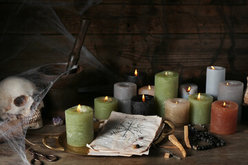 Witch's magic attributes with burning candles on dark wooden table