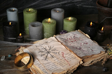 Obraz na płótnie Canvas Witch's magic attributes with spell book and burning candles on dark wooden table