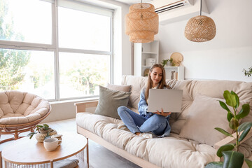 Young woman using laptop on couch in living room