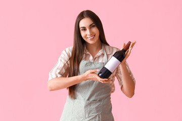 Young woman with bottle of wine on pink background