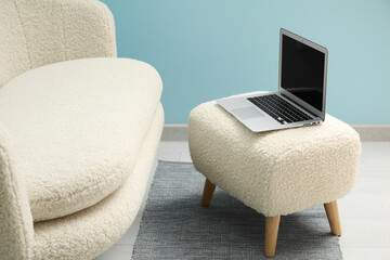 Interior of living room with stylish rug, laptop on white pouf and sofa
