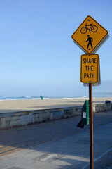 Beach side road sign about sharing path for bicyclist and pedestrians, ocean front walk at Mission beach in San Diego, California