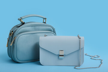 Stylish blue bags on color background