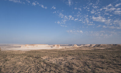 Panorama of hills and ridges with limestone and chalk slopes in the Kazakh steppe at dawn, relief folds in the desert tract of Boszhira in the evening at sunset