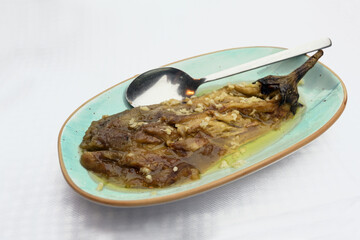 Broiled and peeled eggplant with olive oil and garlic on a turquoise plate, mediterranean dish, copy space, selected focus