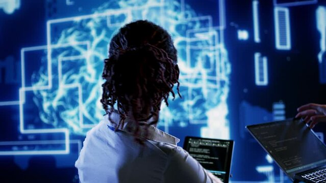 Engineering coworkers updating AI systems, writing intricate binary code scripts on tablet and laptop. Trained technicians using programming to upgrade artificial intelligence simulation model