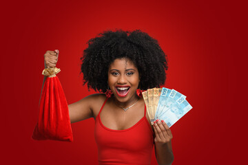 a woman holds shopping bags and Brazilian money, a teenage girl smiles and looks at the camera, wearing a red dress against a red background