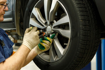Close up of mechanic removes a wheel from car