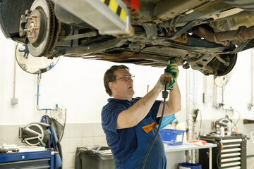 Portrait Shot of a Handsome Mechanic Working on a Vehicle in a Car Service. Professional Repairman...