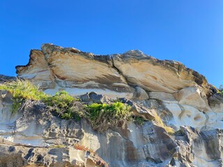 Formation rocheuse sous un ciel bleu. Rocher ocre, blanc et brun ondulant au soleil. Règne...