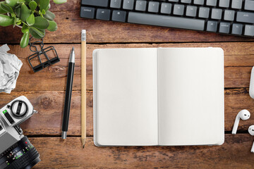 Top view of a blank hardcover leather notebook on a wood office desk table with pencils, mechanical...