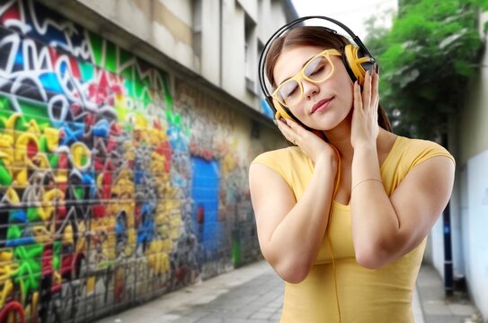 Dancing girl in city. listening music with headphones, AI generated image